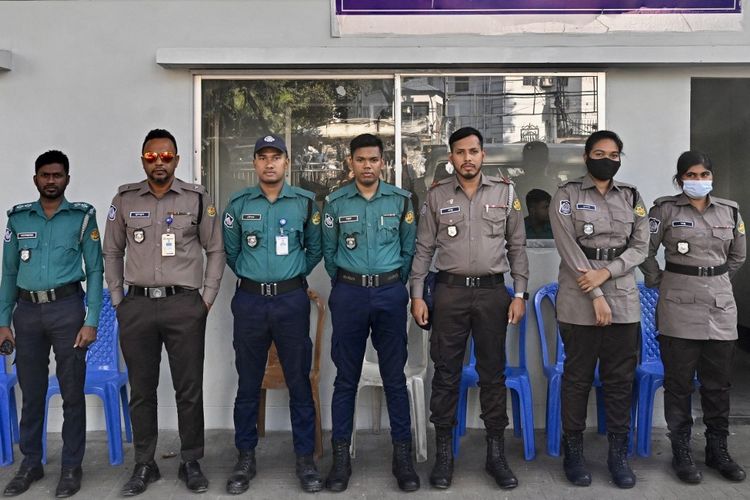 Foto yang diambil pada 18 November 2025 ini menunjukkan personel Kepolisian Bangladesh mengenakan seragam lama (biru toska) dan seragam baru (abu-abu besi dan cokelat kecokelatan) saat berjaga di luar pos polisi di Dhaka. Kepolisian Bangladesh telah memperkenalkan seragam baru sebagai upaya simbolis untuk menandai reformasi dan membangun kembali kepercayaan publik yang terkikis, hanya beberapa minggu menjelang pemilu pertama sejak pemberontakan massal.
