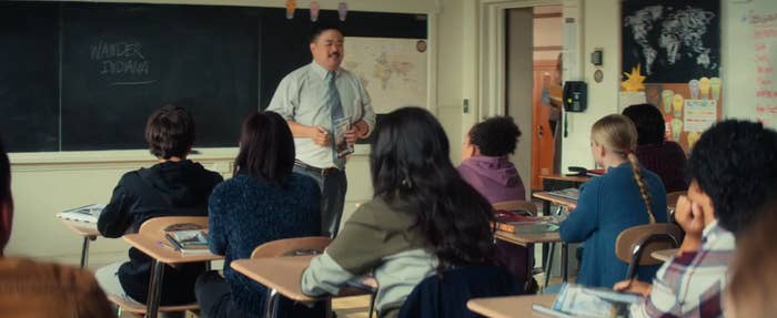 A teacher stands in front of a diverse group of students in a classroom, engaging them in a discussion