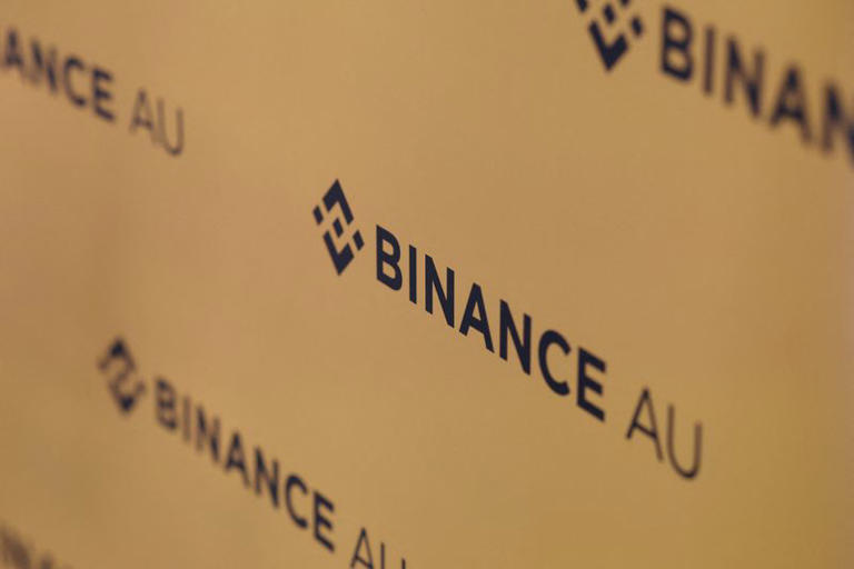 Binance Australia logos are displayed in the backdrop, in Sydney, Australia, November 21, 2025. REUTERS/Hollie Adams