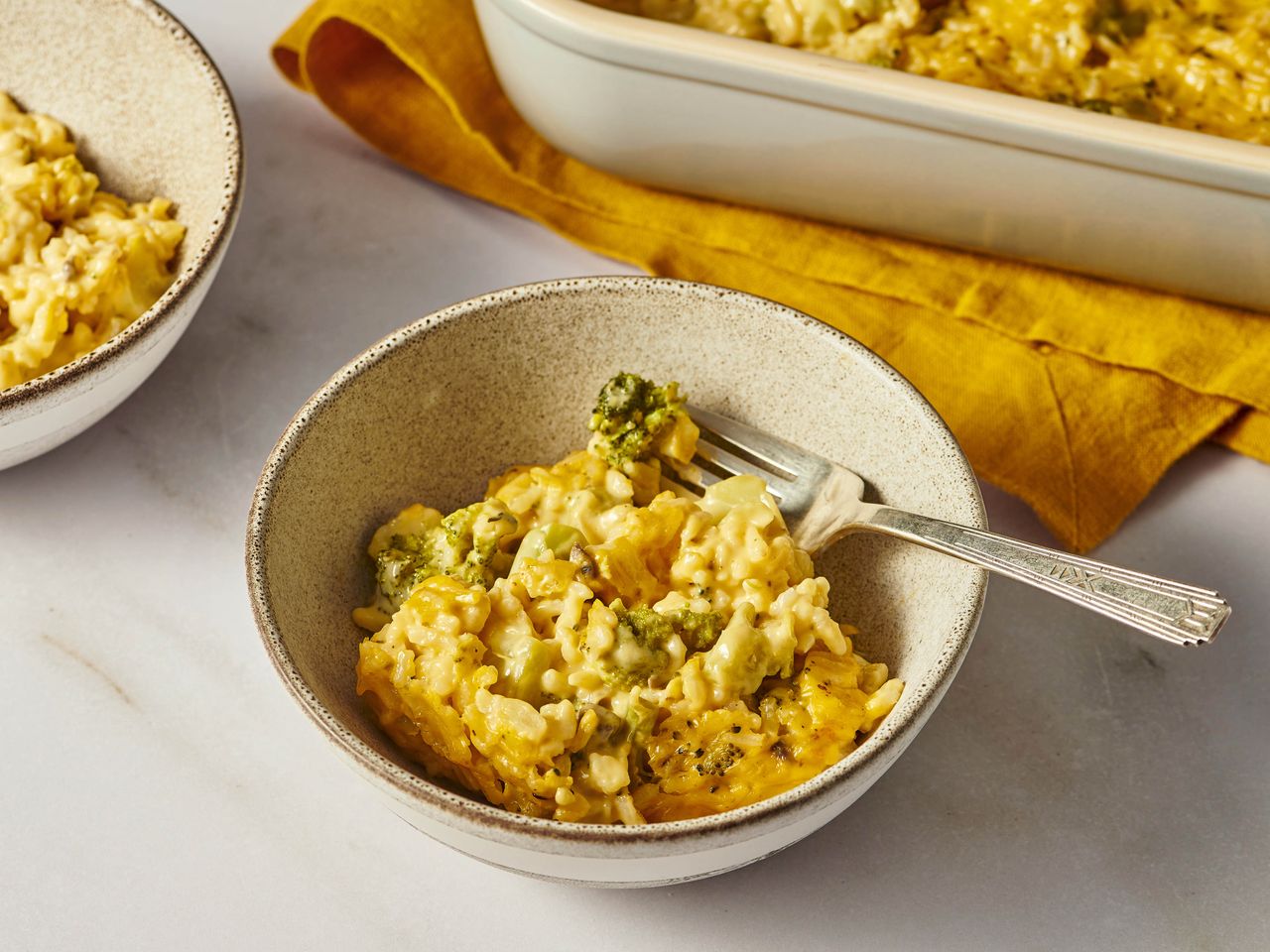 Creamy broccoli and rice casserole served in a bowl and baking dish.