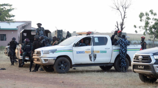 Police officers stand guard outside a school in Nigeria's Kebbi state, where pupils were kidnapped earlier this week.