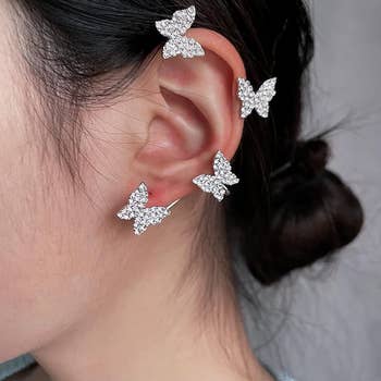 Model wearing elegant butterfly-shaped earrings crawling up ear