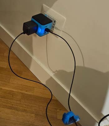 Reviewer's photo of the outlet converter plugged into a wall outlet, with two connected cables, one secured with a cable organizer
