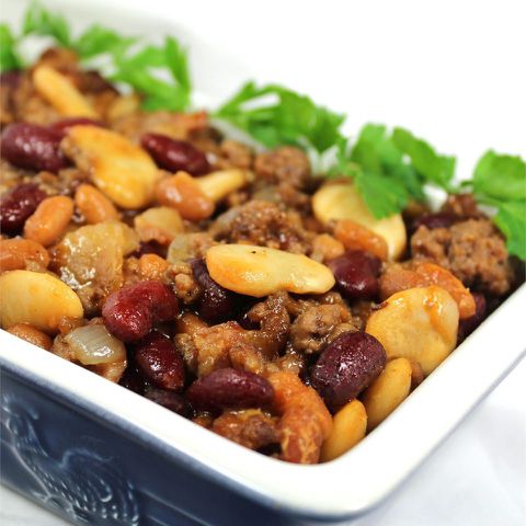 close up view of Calico Bean Casserole garnished with fresh herbs in a baking dish