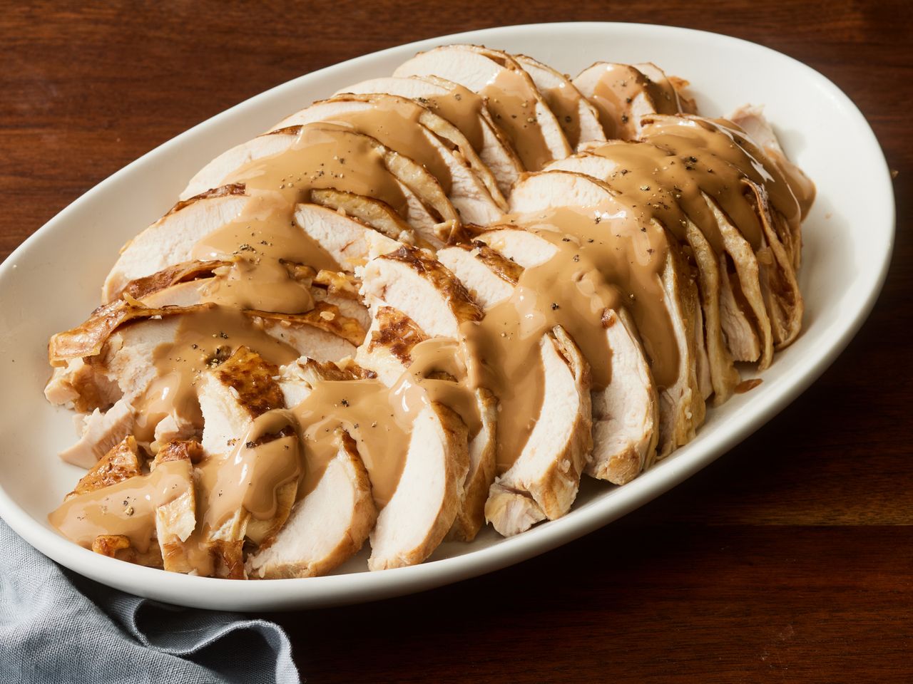 high angle looking at a platter of sliced turkey breast topped with gravy