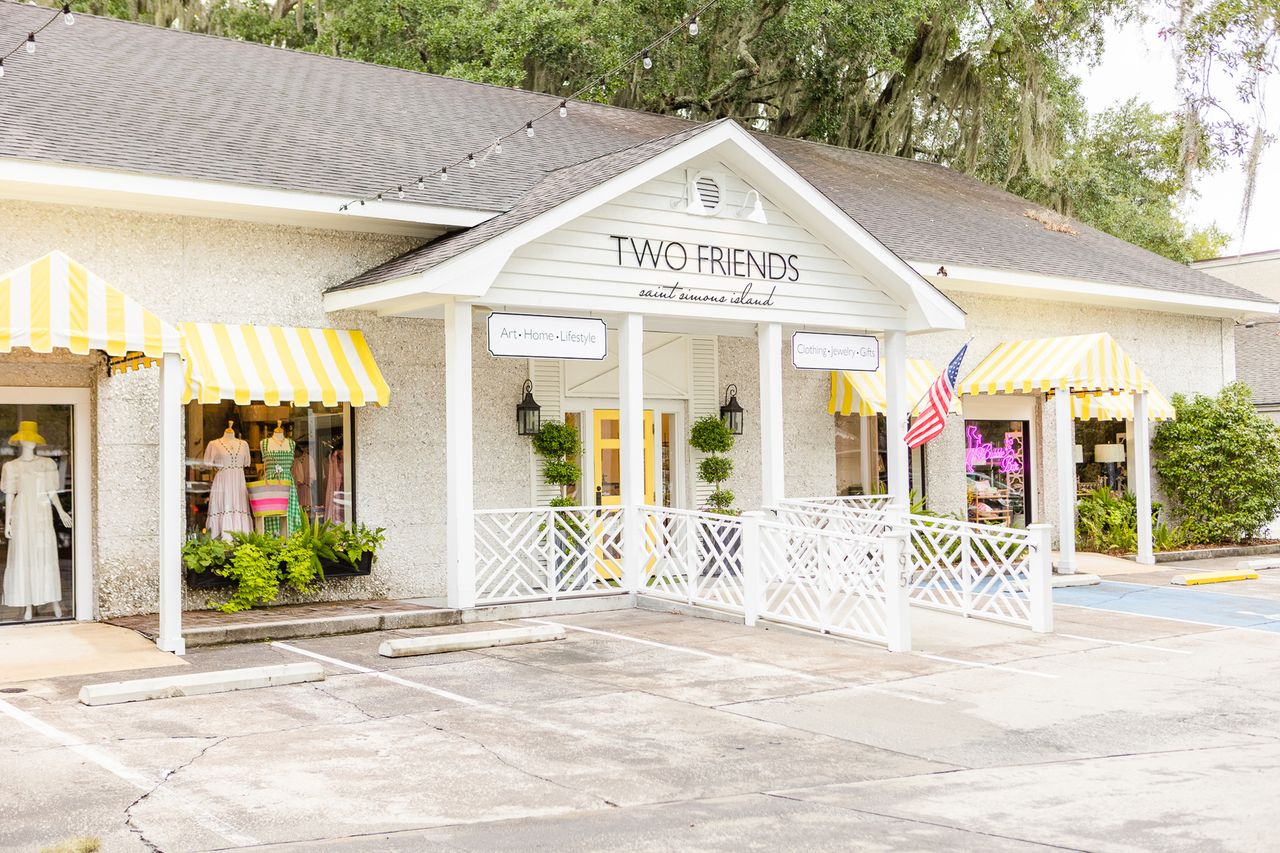 A storefront with a sign reading Two Friends featuring yellowstriped awnings and an American flag on the side