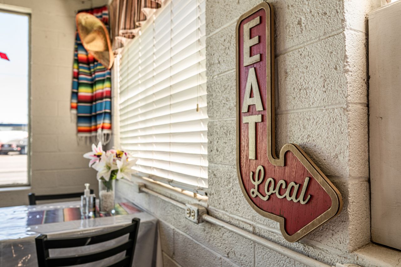 Restaurant interior with a sign reading Eat Local and a festive decor theme