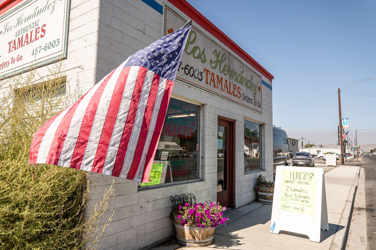 Los Hernandez Tamales storefront with an American flag and signage on the sidewalk