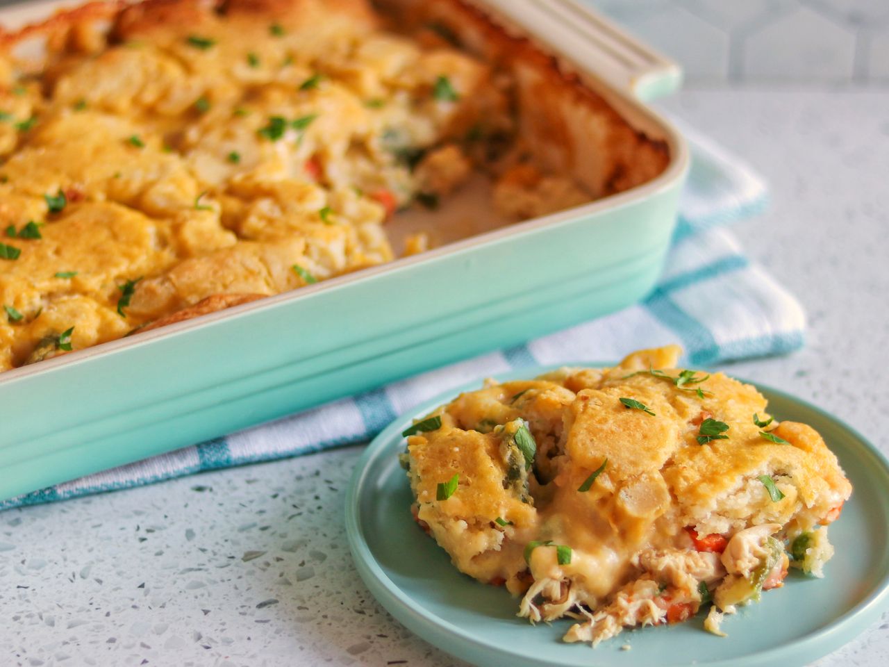 Scoop of Chicken Cobbler on a green plate next to a baking dish