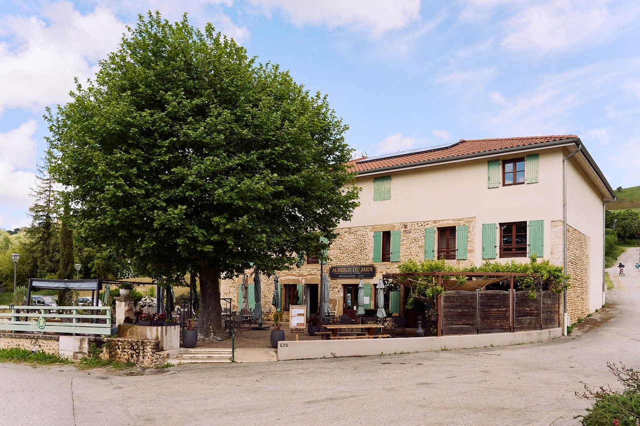 A rustic hotel with outdoor seating and a tree in the foreground