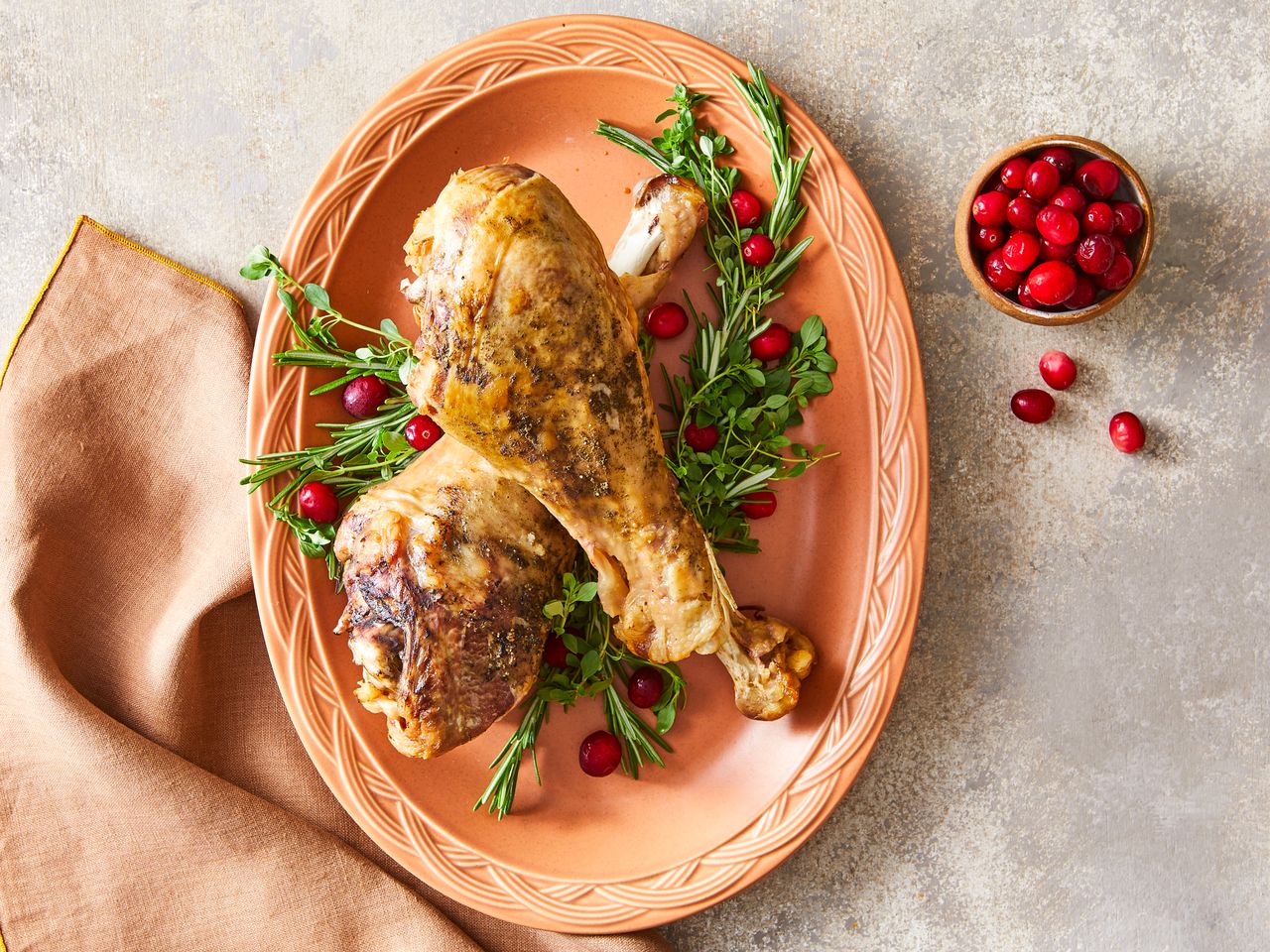 Slow Cooker Turkey Legs on a platter garnished with green herbs and red berries