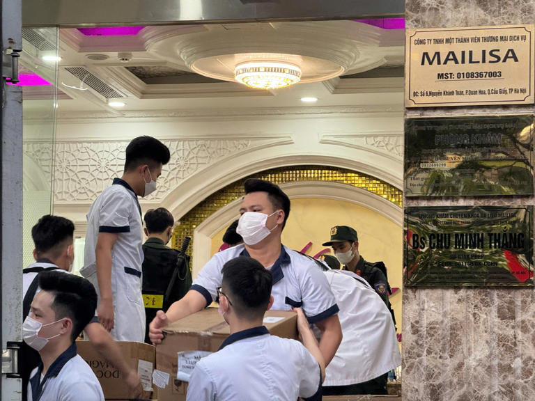 Nhân viên thẩm mỹ viện Mailisa bốc vác các thùng tài liệu, máy móc lên xe của lực lượng chức năng - Ảnh: DANH TRỌNG