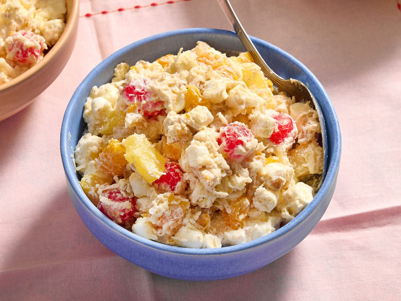 Ambrosia fruit salad in a blue bowl with a spoon.