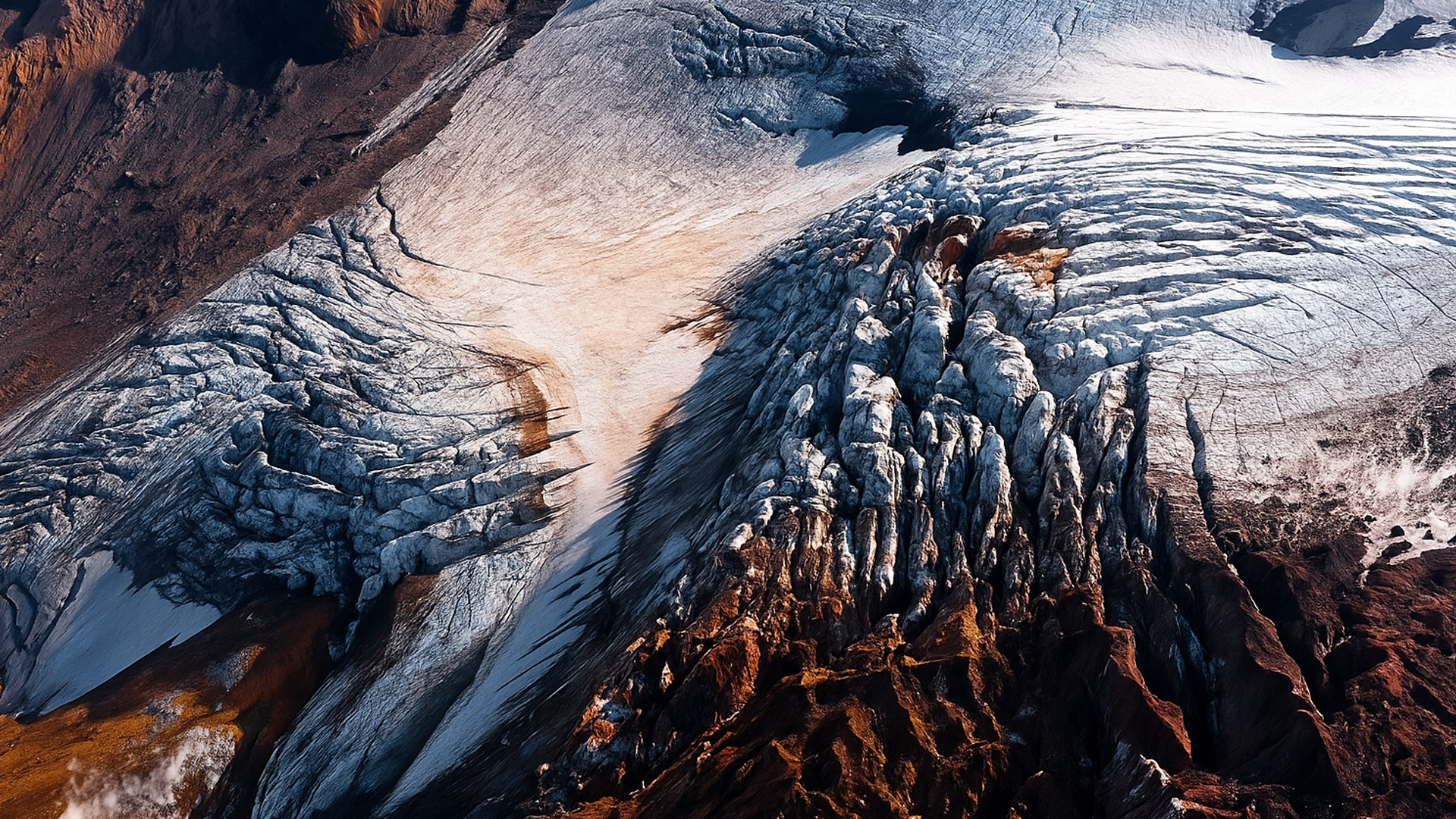 Isbre sprekker gjennom ildfarget fjell