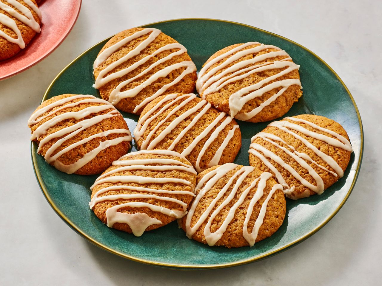 A green plate with iced pumpkin cookies