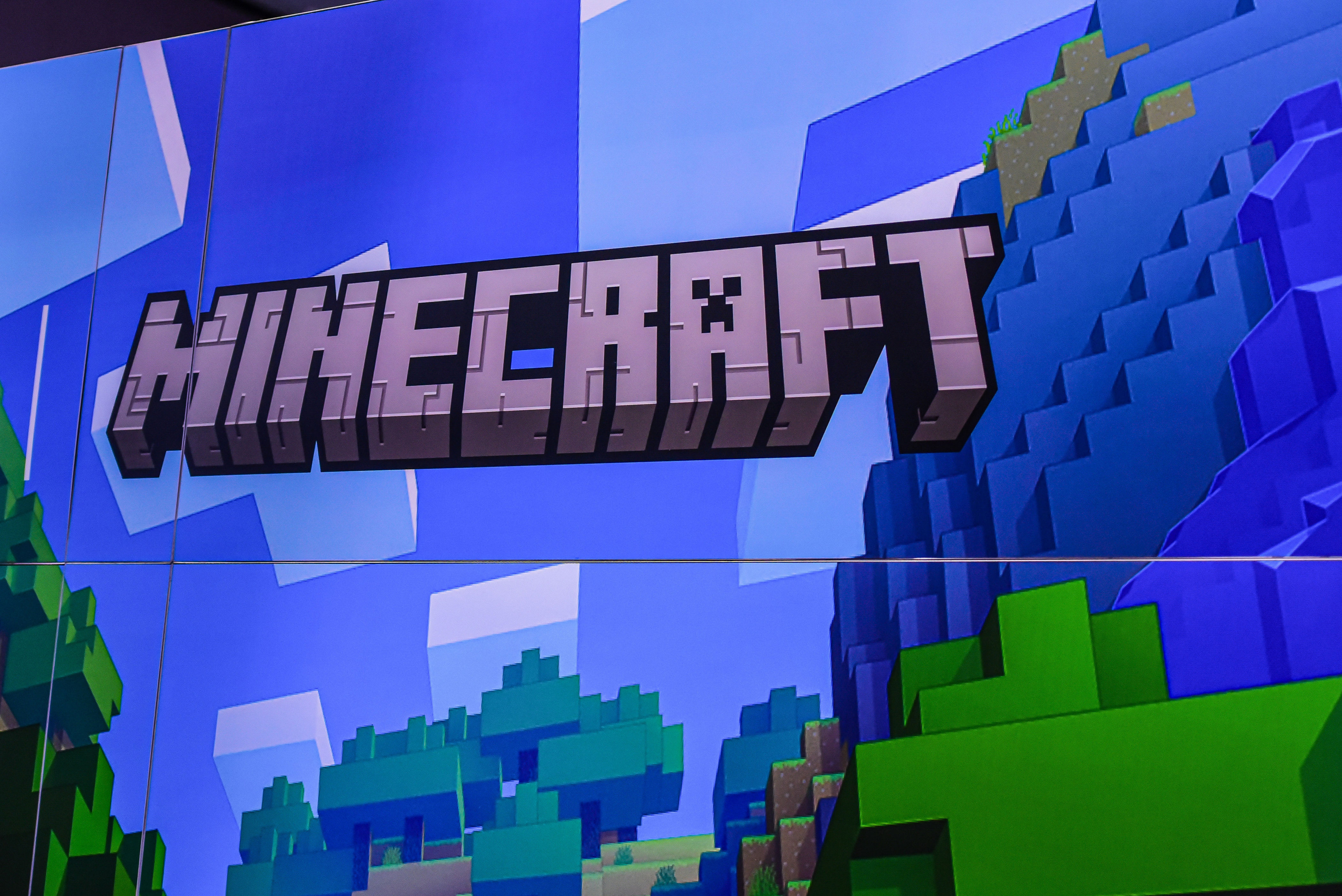 Minecraft logo displayed on a pixelated, blocky background resembling the game's landscape