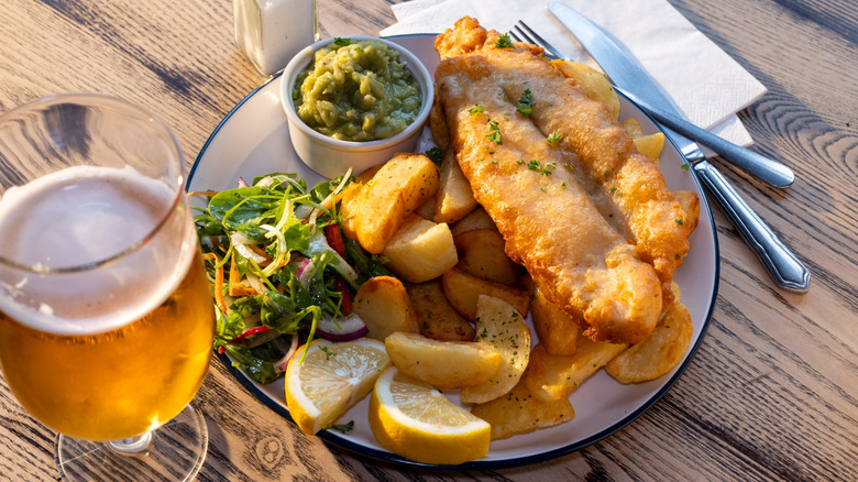 Plate of fish and chips with a side of salad and mushy peas