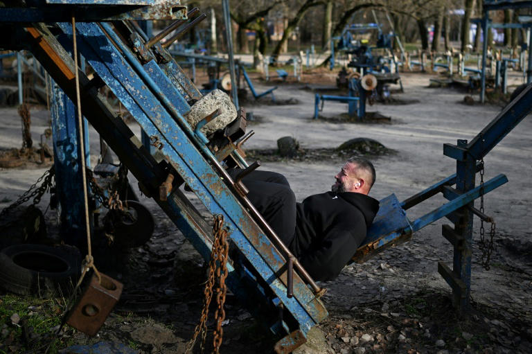 Homem se exercita levantando pedras em uma academia ao ar livre em Kiev, em 24 de novembro de 2025