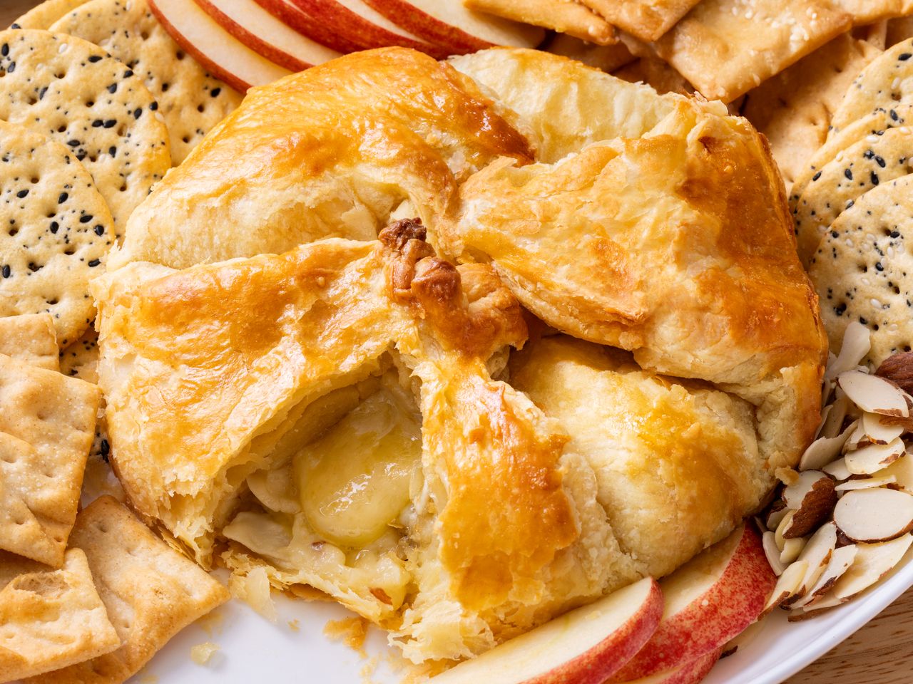 Golden-baked puff pastry with melted brie, crackers, and apple slices.
