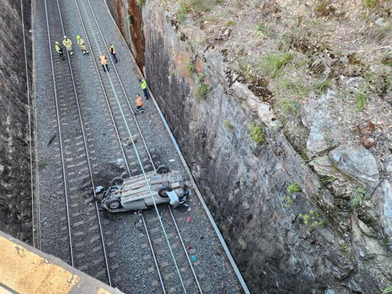 Chaos after car crashes onto train tracks
