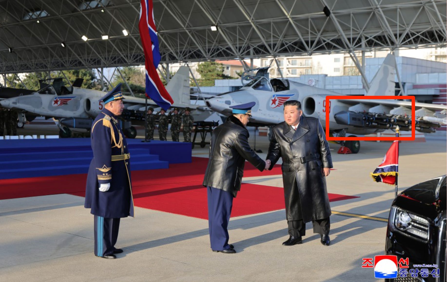 Kim Jong Un shakes hands with a military officer inf ront of a Su-25.