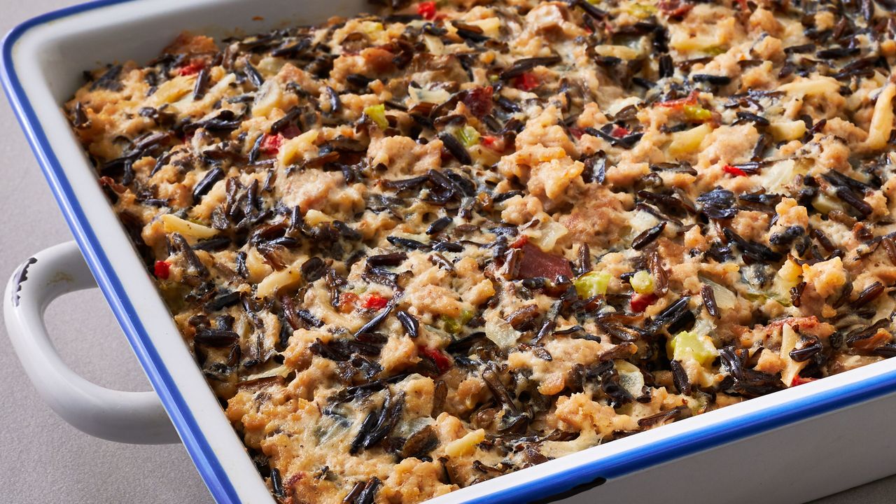A baked wild rice casserole in a white dish with a blue rim featuring visible ingredients like rice diced vegetables and sauce
