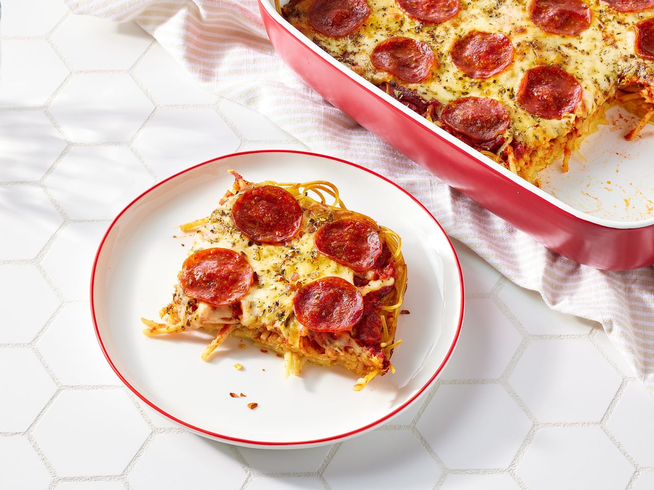 Slice of Spaghetti Pizza next to a casserole dish
