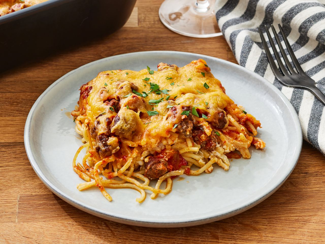 A plate of baked spaghetti topped with cheese and herbs