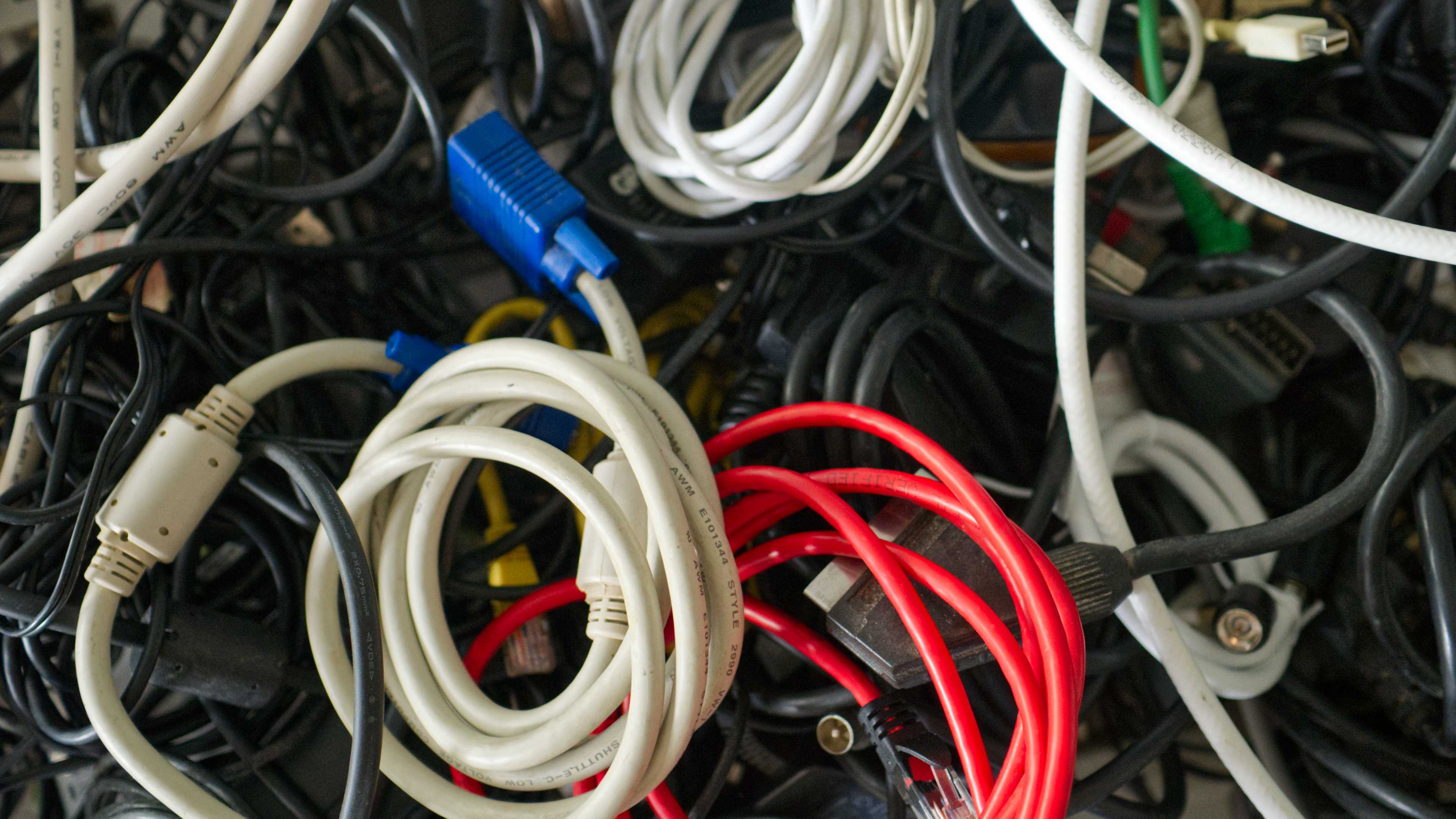 A tangled mess of cables in a box with a VGA and Ethernet cable visible.