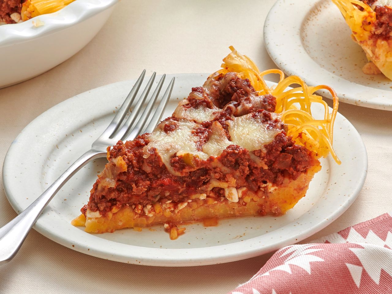 A slice of spaghetti pie on a plate with a fork