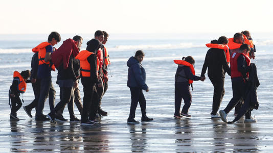 Migrants walk away from the beach after a failed attempt to cross the English Channel to reach Britain, from Petit-Fort-Philippe beach in Gravelines, near Calais, France, September 27, 2025.