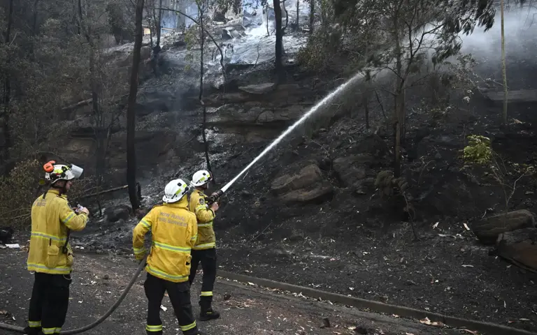 Australian bushfires raze homes in 2 states, firefighter dies