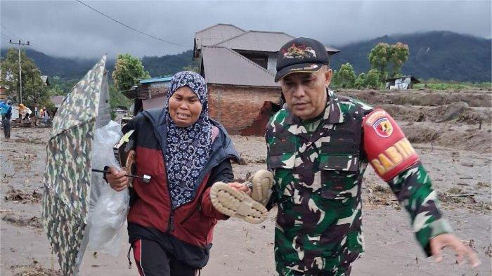 BANJIR BANDANG- Prajurit TNI saat membantu seorang warga melewati lumpur yang terbawa banjir bandang di Jorong Toboh, Nagari Malalak Timur, Kecamatan Malalak, Kabupaten Agam, Rabu (26/11/2025). (Dokumentasi/Warga (Dessy Rahma Yanti))