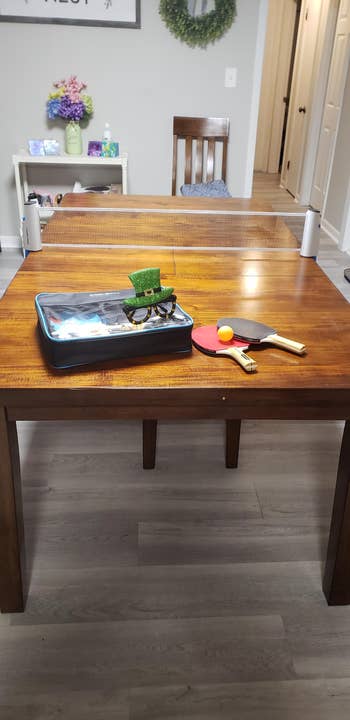 Table with a portable ping pong setup, two paddles, and a ball