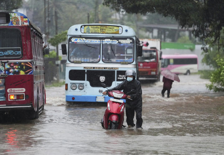 Seorang pengendara sepeda motor mendorong motornya saat banjir di Kelaniya, Sri Lanka, Jumat (28/11/2025). Foto: Thilina Kaluthotage/Reuters