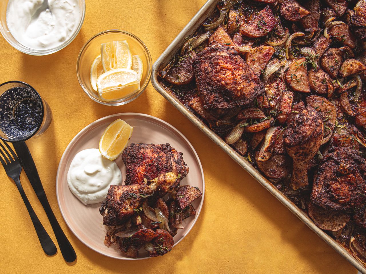 Sheet pan with roasted chicken and potatoes plate served with yogurt and lemon slices
