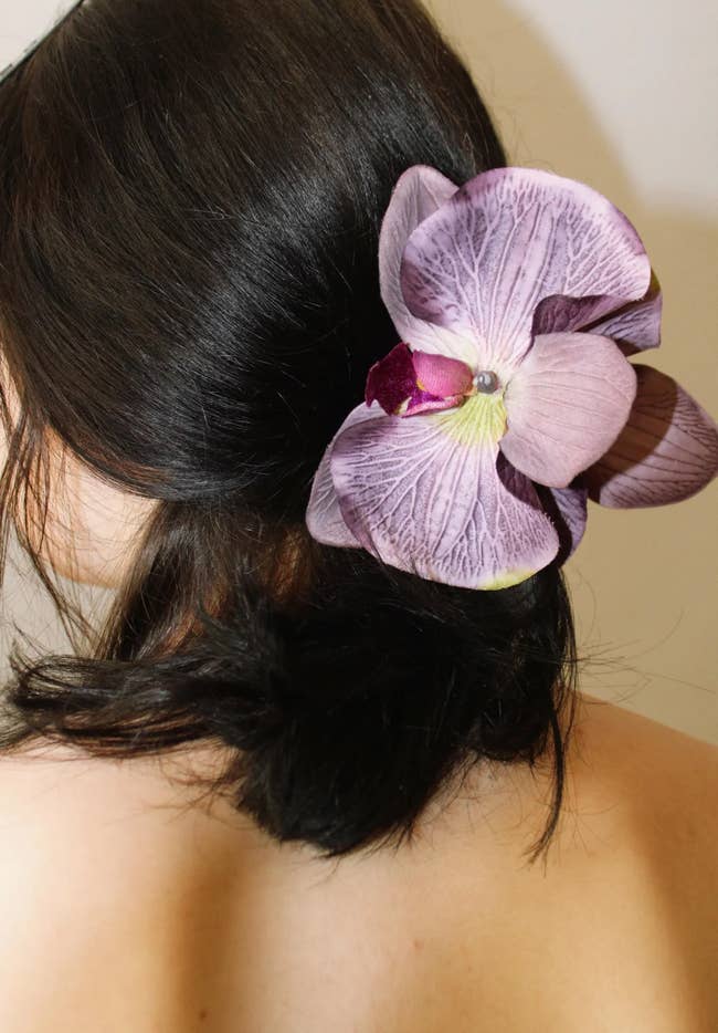 A model with a large, orchid hair accessory pinned in hair