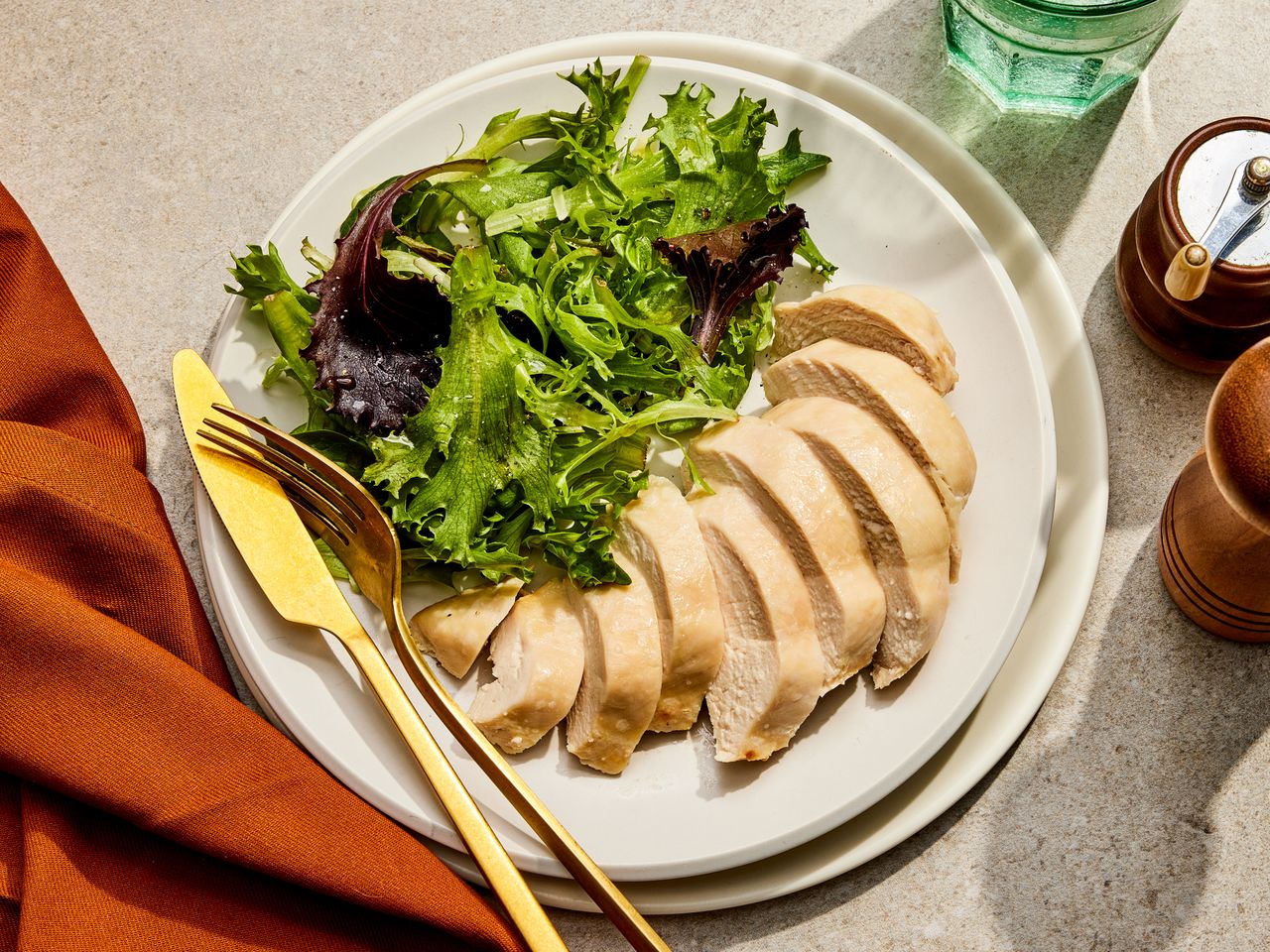 A plate of sliced chicken breast served with mixed green