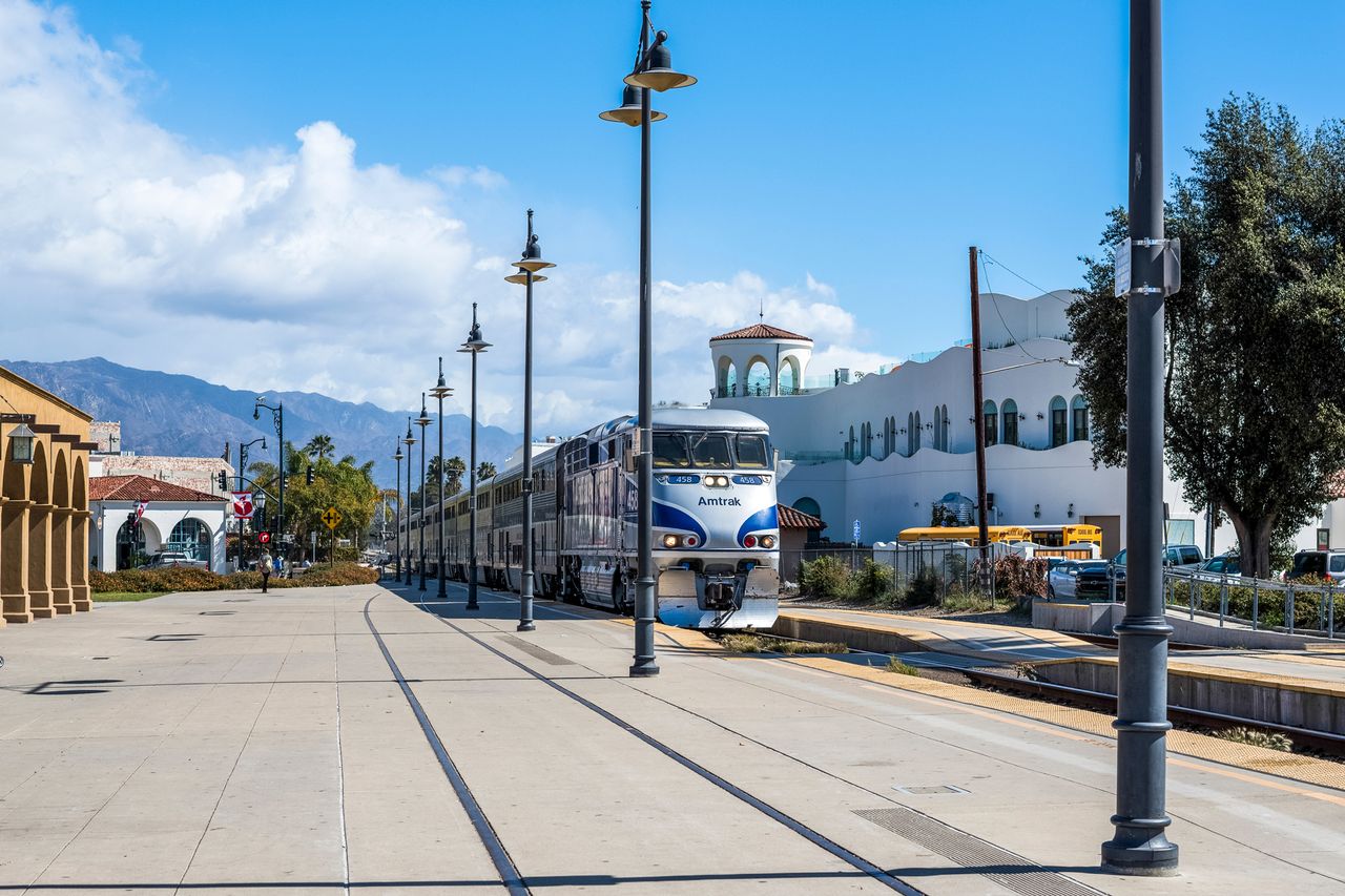A train at a station platform with buildings in the background
