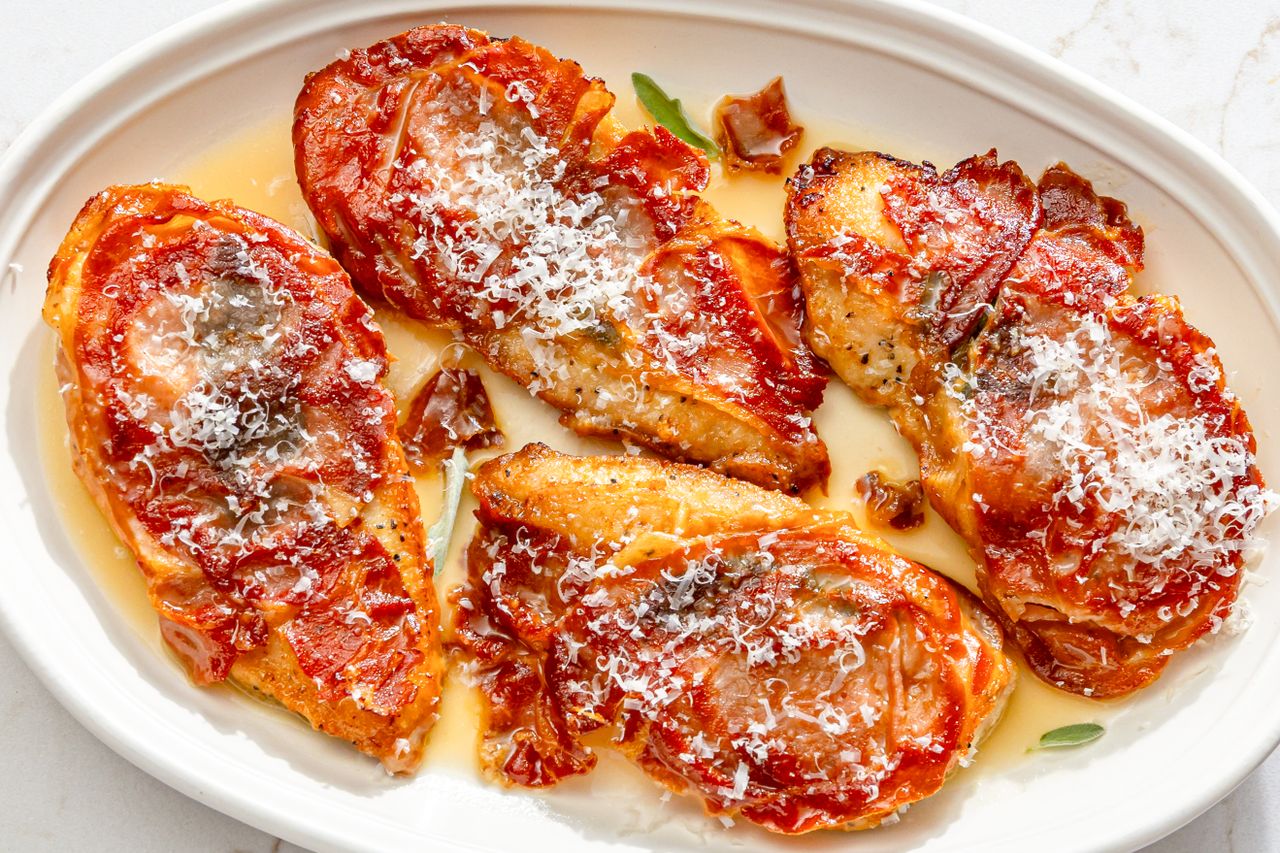 Chicken saltimbocca plated topped with crispy prosciutto and grated cheese