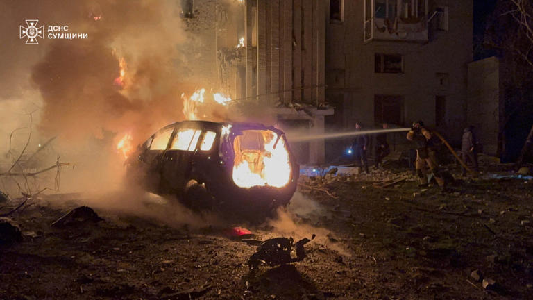 Firefighters working to extinguish a fire following a drone attack on a residential building in Okhtyrka, Sumy region, on 8 December (AFP)