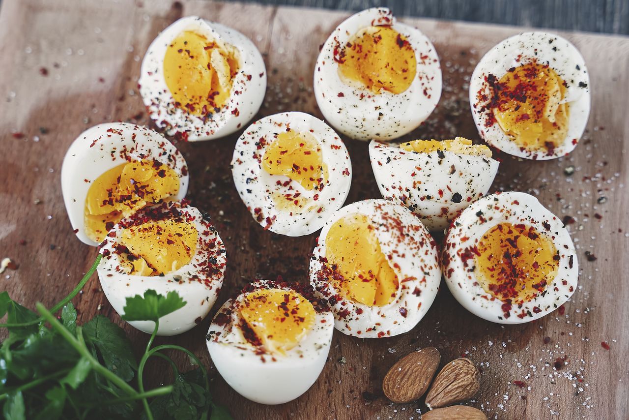 Hardboiled eggs halved and seasoned with spices garnished with fresh herbs and almonds