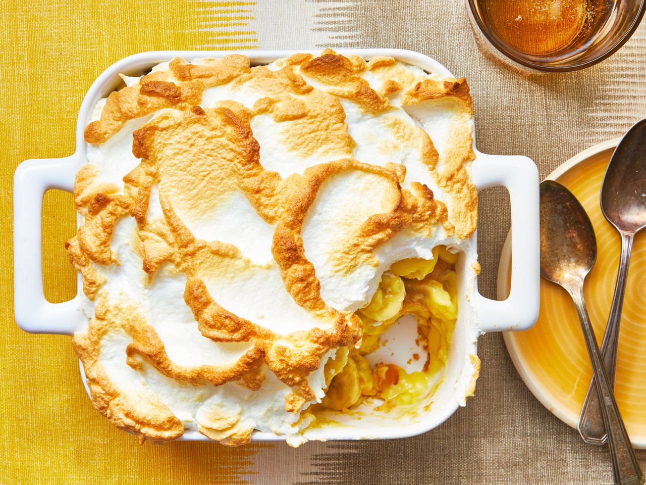 a square pan of banana pudding on a yellow linen