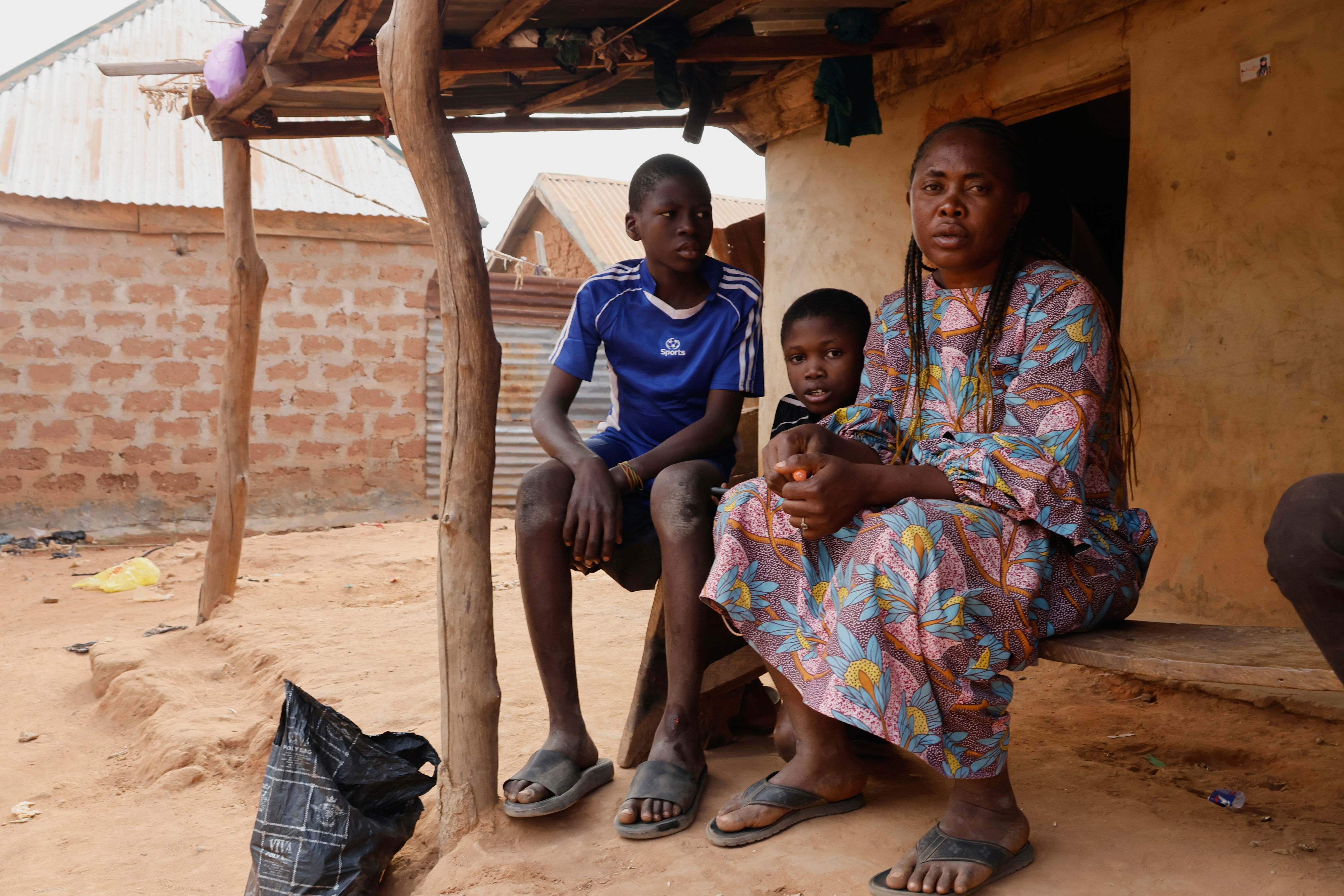 Precious Njikonye, right, the mother of a student at St. Mary's Catholic School, who was abducted by gunmen and later released, sits outside her house in Papiri, Nigeria (AP Photo/Afolabi Sotunde)