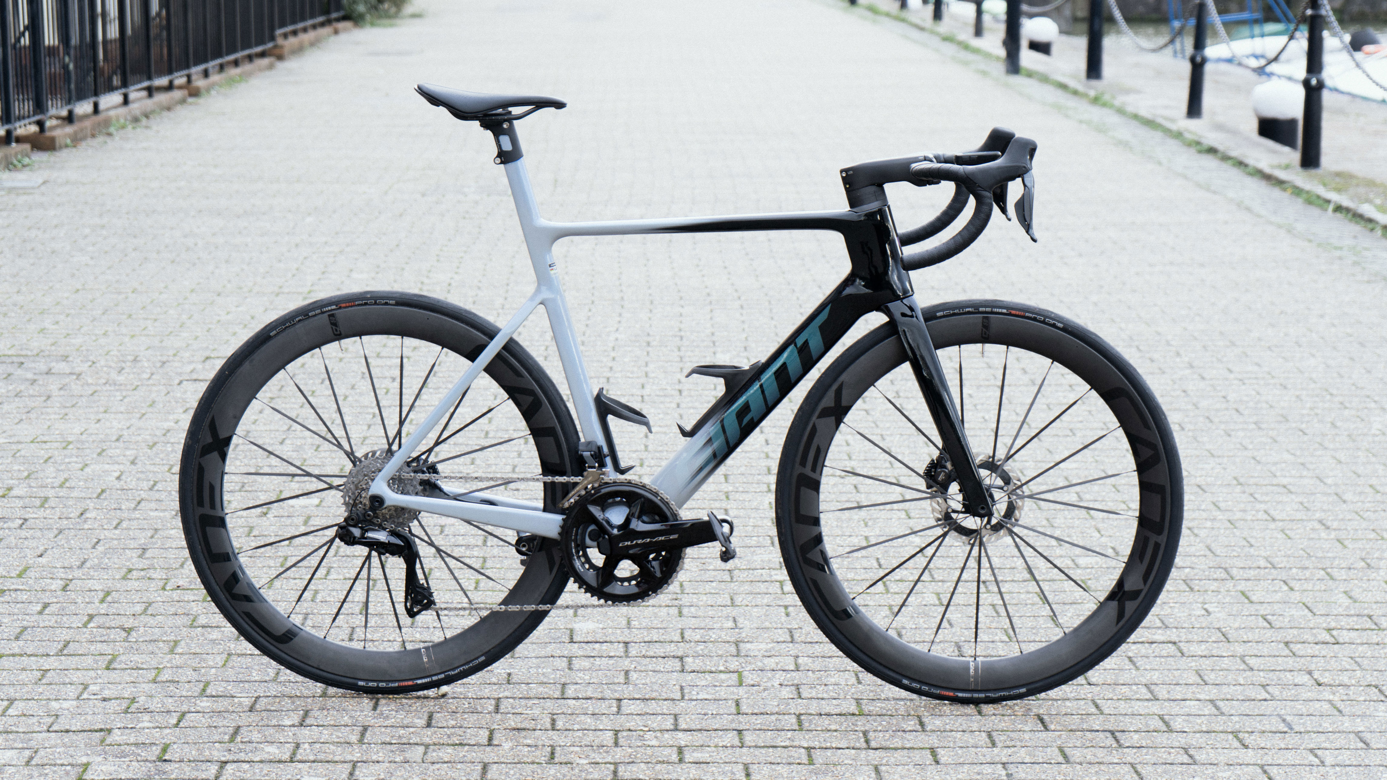 A grey and black bike stands on a brick pavement