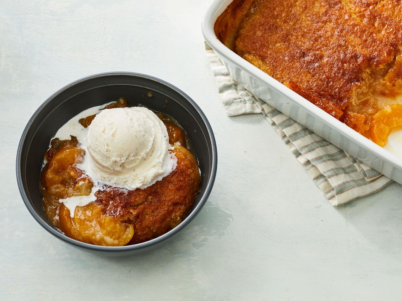 Southern Living Fresh Peach Cobbler with a serving scooped into a bowl with ice cream