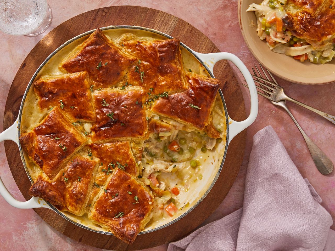 Southern Living Skillet Chicken Pot Pie with Puff Pastry in the dish with a serving out beside it