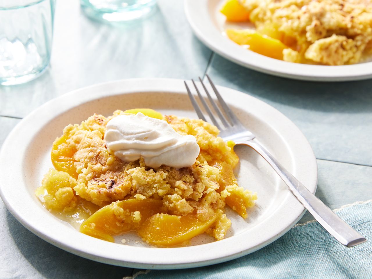 Peach cobbler dump cake served on a plate with whipped cream and a fork