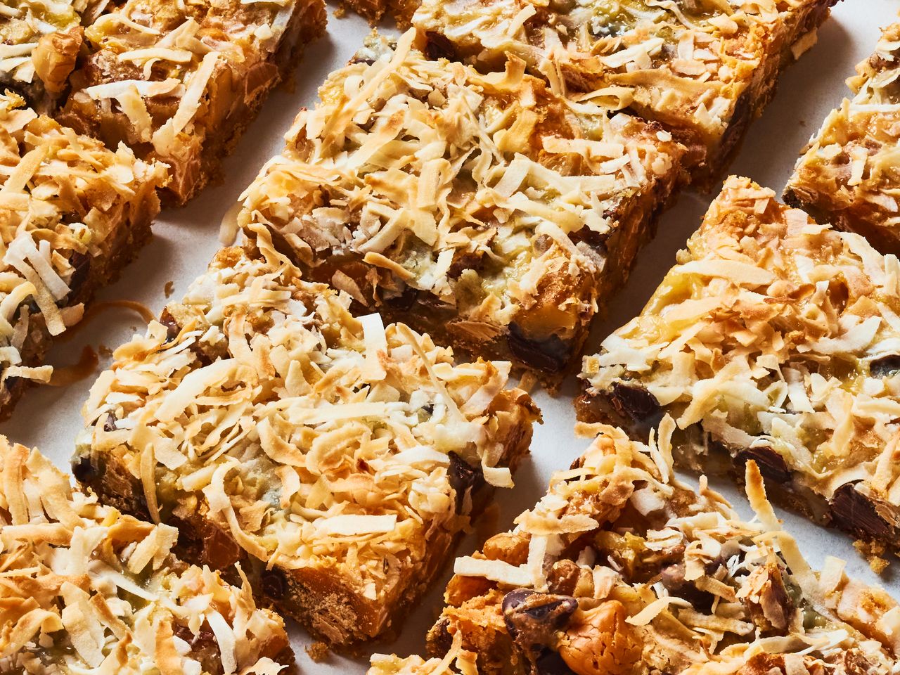 Tray of sevenlayer dessert bars topped with coconut shavings