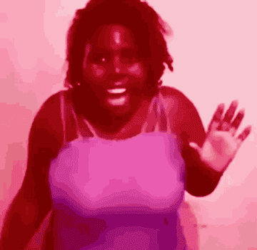 A person energetically dances and waves at the camera with a joyful expression
